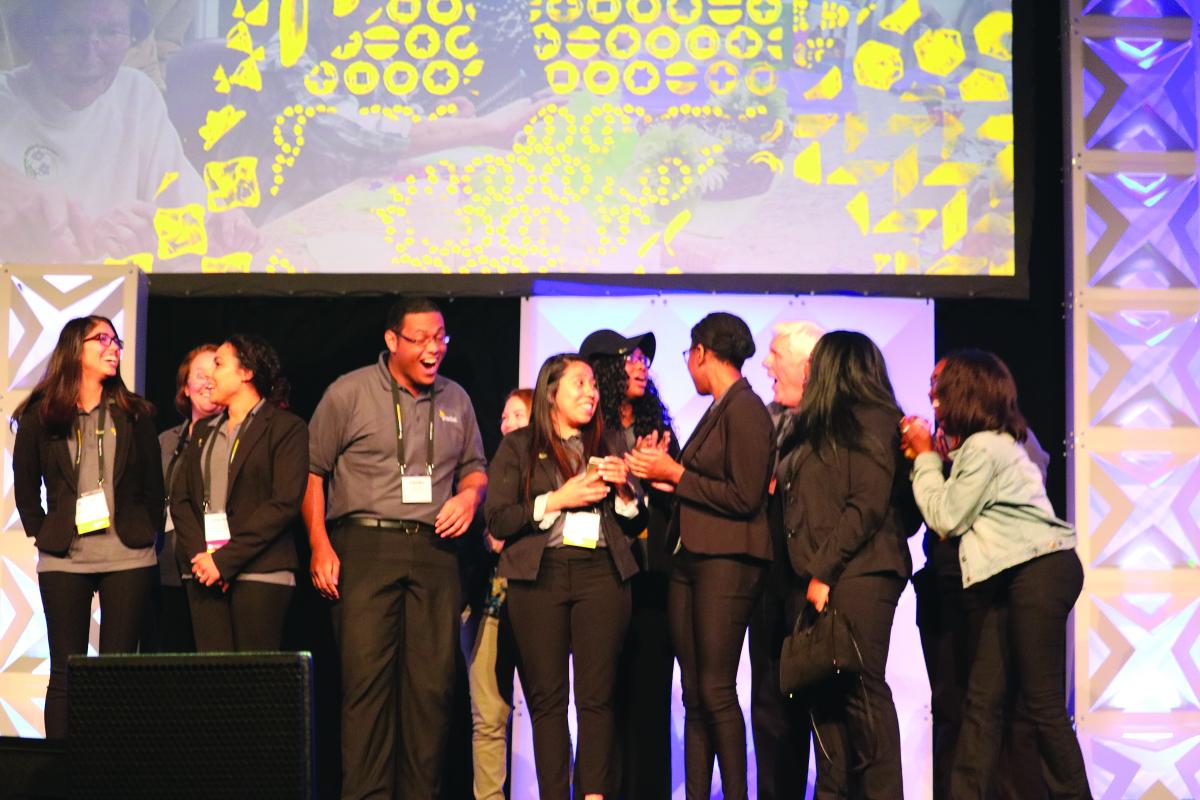 Students celebrate their first place trophy for Sam's Club Step Up for Small Business award at the Enactus USA Expo