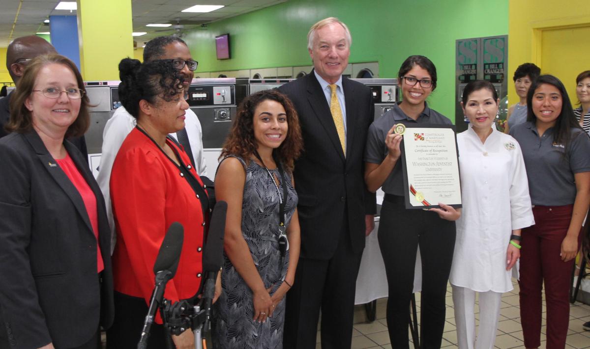 Washington Adventist University faculty, staff and students join Peter Franchot, comptroller of Maryland (center) and Yumi Hogan, the first lady of Maryland (second from right), at Rainbow Coin Laundry for a Sam's Club award ceremony.