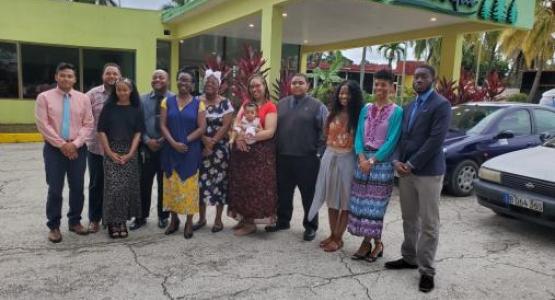 Sandro Miranda, Youth Ministries Director Jason Ridley, Courtney Cantrell, Carl McClatchie, Blissa Letang, Deja Dockery, Young Adult Ministries Director Charde Hollins (holding Addie Joy), Matthew Scone, Brittany Cantrell, Tara Carmen and Tanitoluw Ajaiyeboa stand in front of a church in Cuba where they preached.