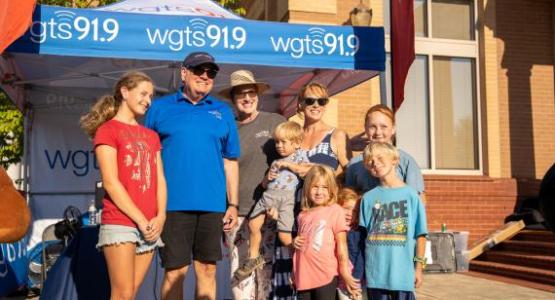 2.	Afternoon hosts, Johnny and Stacey Stone, pose with a family in front of the WGTS broadcast tent.