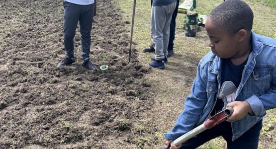 Josiah, a young boy who attends the Cedars of Lebanon church, tills soil to cultivate sweet bell peppers. Cedars of Lebanon Youth Plant Garden, Allegheny East Conference, Garden of Hope, Doris Johnson