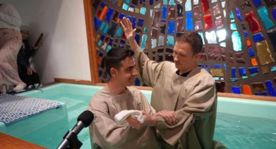 Adam Bially (right), Blue Mountain Academy chaplain, baptizes Mark Mikle, one of six students who got baptized at the end of last school year.