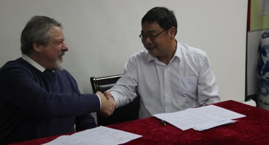 Principal Dave Morgan signs sister school agreement with Fang Wangdong of the Lin’an High School in China. 