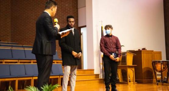 Pastor Sanghae Kim reads the baptismal vows to candidates Kyle Williams and Joseph Berry.