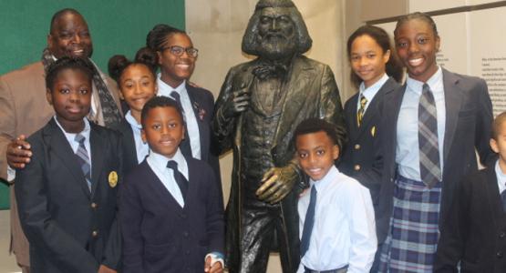 George E. Thornton, Sr., principal of the Dupont Park Adventist School, and eight students (left of the statue) Imani Yates, Simone Scott, Ayanna McInnis, Christopher Henderson, (right of the statue) Chase McClure, Jaffe Watkins, Dorian Donovan and Lawrence Talbert stand next to a Frederick Douglass statue.