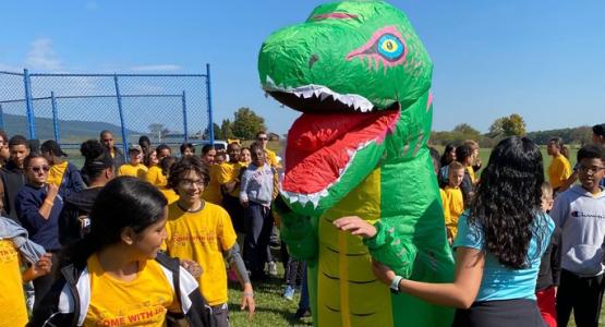 Blue Mountain Academy students—and a friendly dinosaur—play a game similar to kickball. Blue Mountain Academy, Pennsylvania Conference, Sports Fest, Burney Culpepper