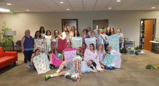Twenty-one experienced- and beginner-student sewers, including co-leader Dorcas Sweeny (left), display some of the 120 pillowcases they donated to a local nursing home.