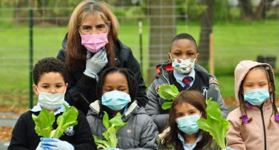 A group of kindergartners from Huntingdon Valley Christian Academy, along with teacher’s aide Aida Torres, proudly show the first fruits from their community garden. Huntingdon Valley Christian Academy, Aida Torres