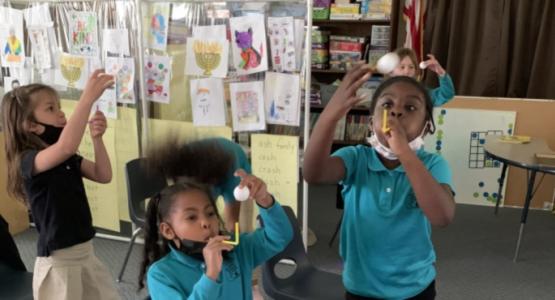 Kindergarteners and first-graders at the Harrisburg Adventist School blow air through straws to hover their ping pong balls. Pennsylvania Conference Education, Zoom