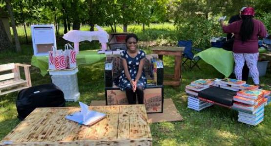 Sixth-grader Sobrina Sterling sits on a piece of furniture made by the 11th grade physics class.