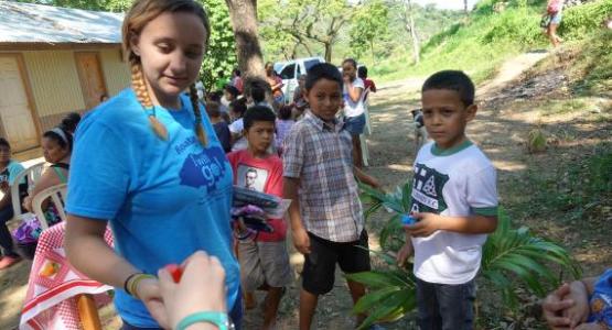 Senior Lori Prendergast from the Highland Adventist School in Elkins, W.Va., gives small gifts to children waiting in line at the health clinic.