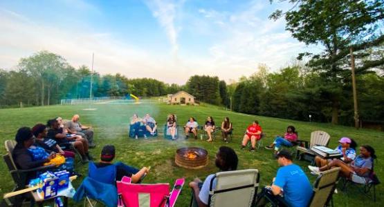 Campers relax by the fire at the 2022 Young Adult Retreat.