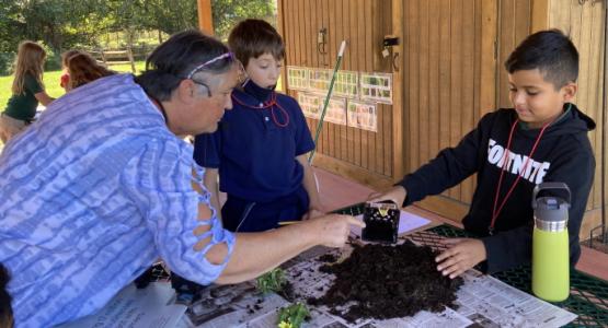 Dainett Bowers, who teaches grades 3–5, inspects soil with fourth-grade students Lucas Baker and Jayden Vasquez. Manassas Adventist Preparatory School, Outdoor Education Pavilion