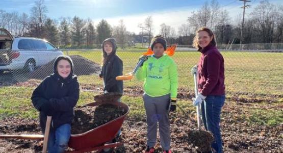 Leona Bange (right), the conference’s education superintendent, and students from the York Adventist Christian School help to spread new rubber mulch on the school’s playground.