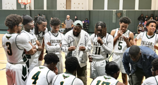 The boys’ varsity basketball team huddle during a timeout.