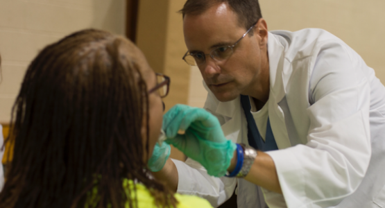 Kettering College (Ohio) physician assistant and Professor Tim Scanlon performs an oral exam on an attendee during the Ephesus church-sponsored Community Health Emphasis Weekend.