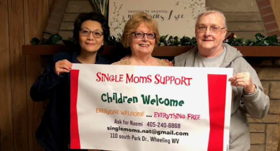 Surrounded by church members Annabel Murphy and Sue Walter, Naomi Tricomi, pastoral assistant for the Weirton/Wheeling, W.Va., district, together display an advertising banner for a Single Mom’s Ministries event.