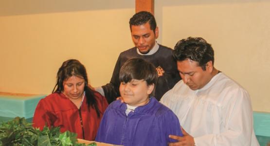 Enmanuel A. Freites Perez (in back), assistant pastor of the Vandalia church plant, baptizes (left to right) Marcia Hernandez, her son Christian and husband, Aslih.