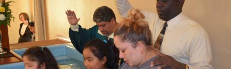 Pastor Pedro Simpson baptizes the Martinez family as  evangelist Julio Chazarreta looks on