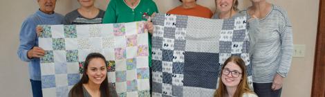 Lois Ruth (standing, second from right) and the Columbus Eastwood Women’s Ministries team hold two handmade quilts for infants at a local hospital.