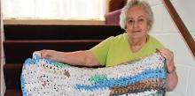 Shirley Crouser shows a soft mat made from colorful plastic grocery bags which will bring warmth to a homeless person.
