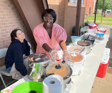 Members April Johnson and Mo Maitley display prepared food at the church’s soup kitchen